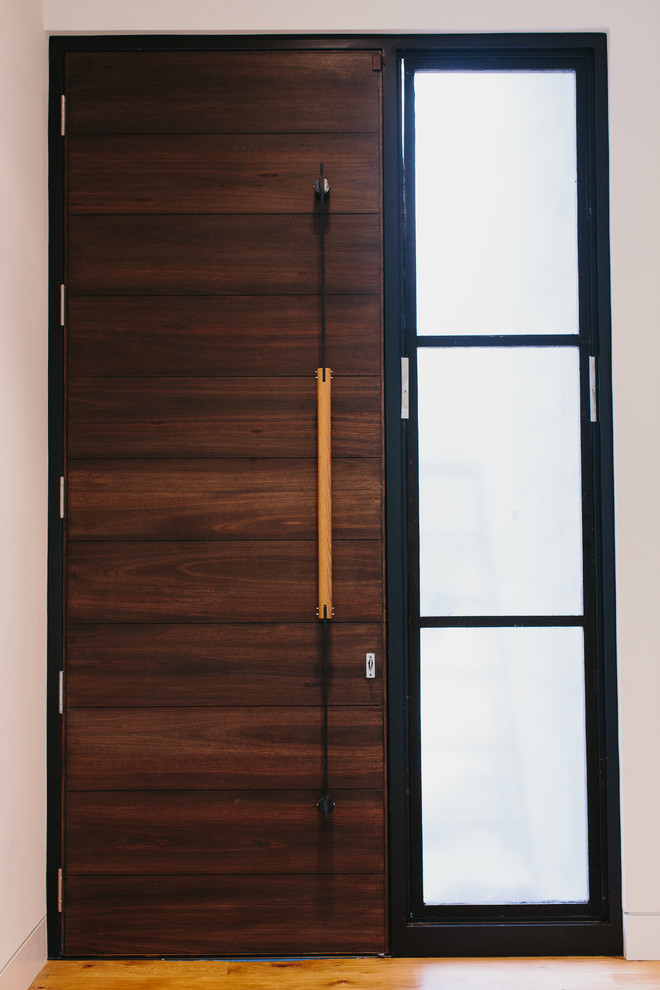 Cette photo montre une petite porte d'entrée moderne avec un mur blanc, un sol en bois brun, une porte simple et une porte en bois foncé.