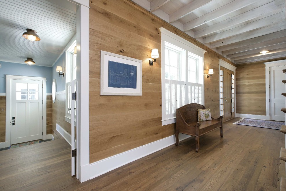 Idee per un corridoio classico con pareti blu, pavimento in legno massello medio, una porta singola e una porta bianca