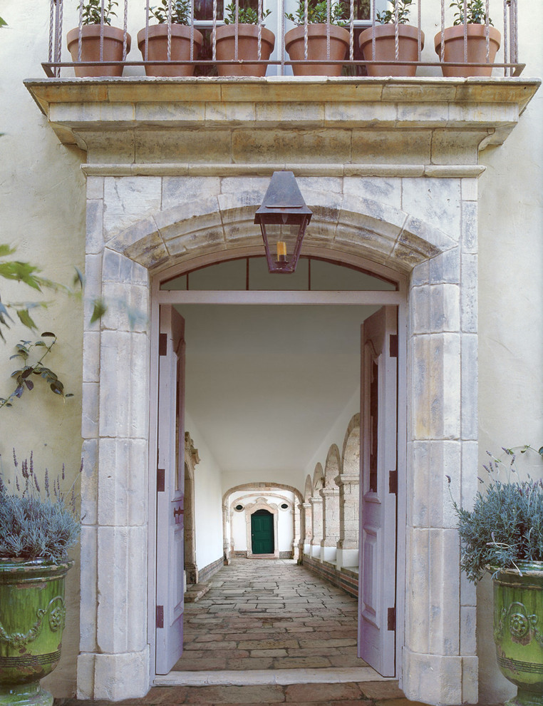 На фото: входная дверь среднего размера в средиземноморском стиле с бежевыми стенами, полом из известняка, двустворчатой входной дверью и серой входной дверью с