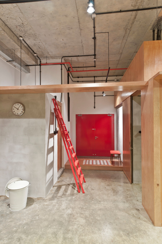 Foto di un corridoio design con pareti bianche, pavimento in cemento, una porta a due ante e una porta rossa