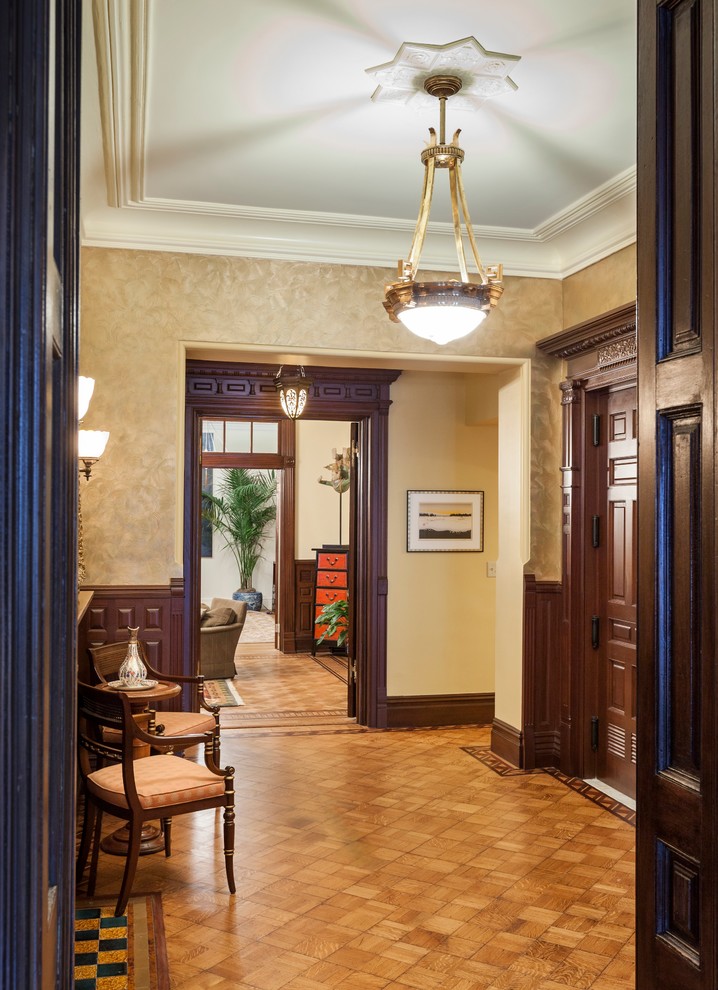 Imagen de entrada clásica con paredes beige, suelo de madera en tonos medios y puerta de madera oscura