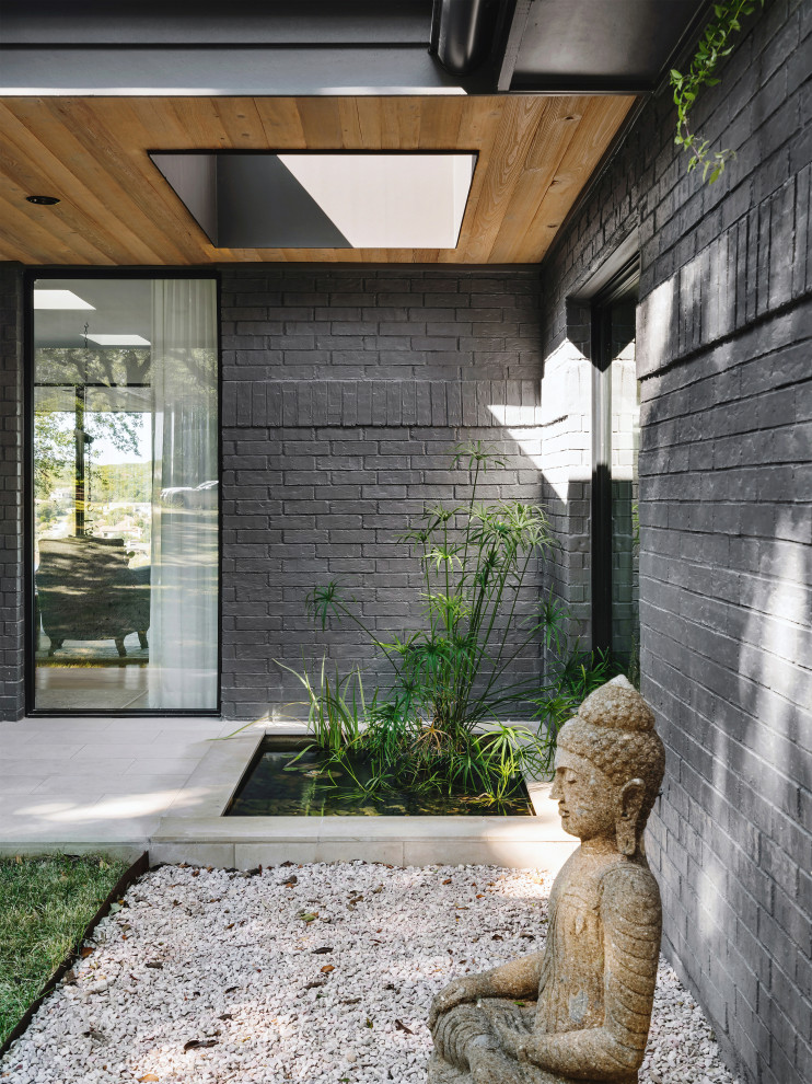 Idée de décoration pour une grande porte d'entrée design avec un mur noir, un sol en calcaire, une porte simple, une porte noire, un sol gris, un plafond en bois et un mur en parement de brique.