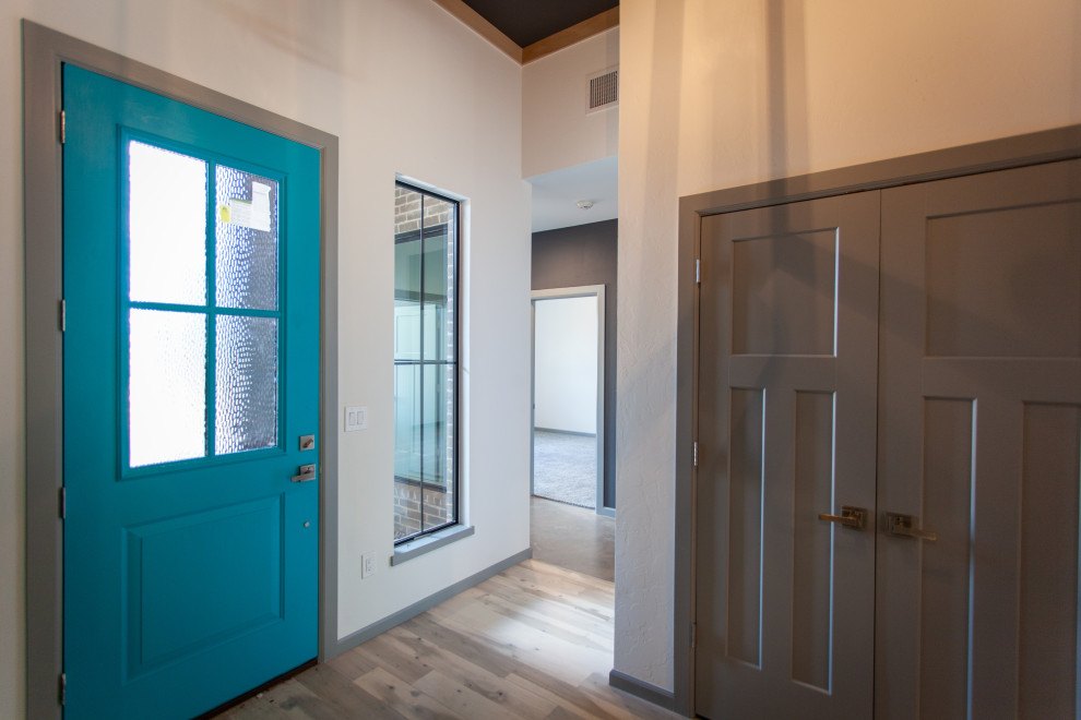 Réalisation d'une porte d'entrée minimaliste de taille moyenne avec un mur marron, un sol en vinyl, une porte simple, une porte bleue et un sol gris.