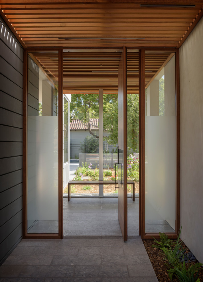 Пример оригинального дизайна: прихожая в стиле модернизм с бежевыми стенами, гранитным полом, поворотной входной дверью, входной дверью из дерева среднего тона и серым полом