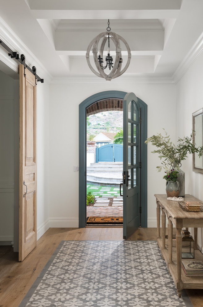 Bild på en lantlig ingång och ytterdörr, med vita väggar, ljust trägolv, en enkeldörr, en blå dörr och beiget golv
