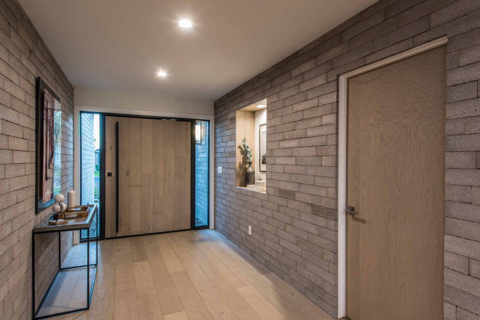 Modelo de hall contemporáneo con suelo de madera clara, puerta pivotante, puerta de madera en tonos medios y suelo beige