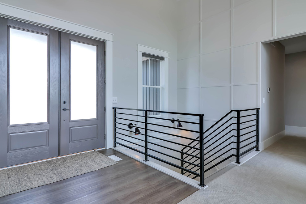 Idee per un ingresso minimal con pareti bianche, una porta a due ante, una porta grigia, pavimento beige e pavimento in laminato