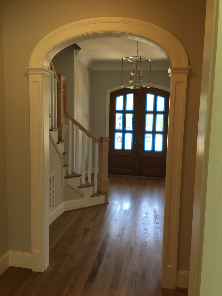 This is an example of a medium sized country foyer in Raleigh with grey walls, medium hardwood flooring, a double front door, a dark wood front door and brown floors.
