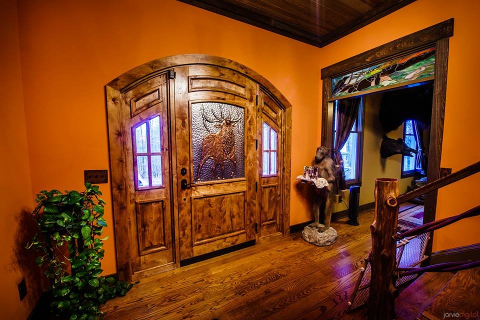 На фото: большое фойе в стиле кантри с входной дверью из дерева среднего тона, оранжевыми стенами, паркетным полом среднего тона, одностворчатой входной дверью и коричневым полом с