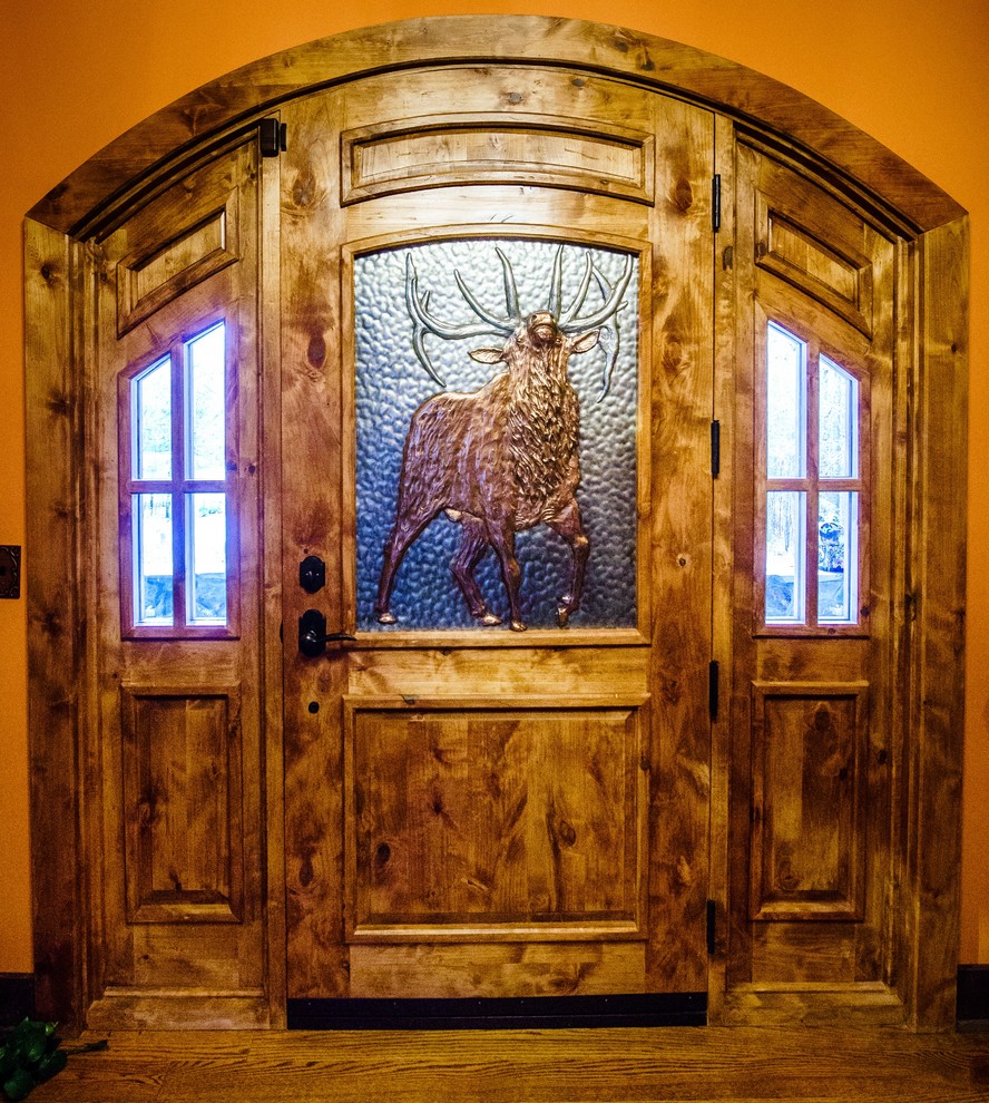 Idée de décoration pour une grande porte d'entrée craftsman avec un mur orange, une porte simple, une porte en bois foncé, un sol marron et un sol en bois brun.