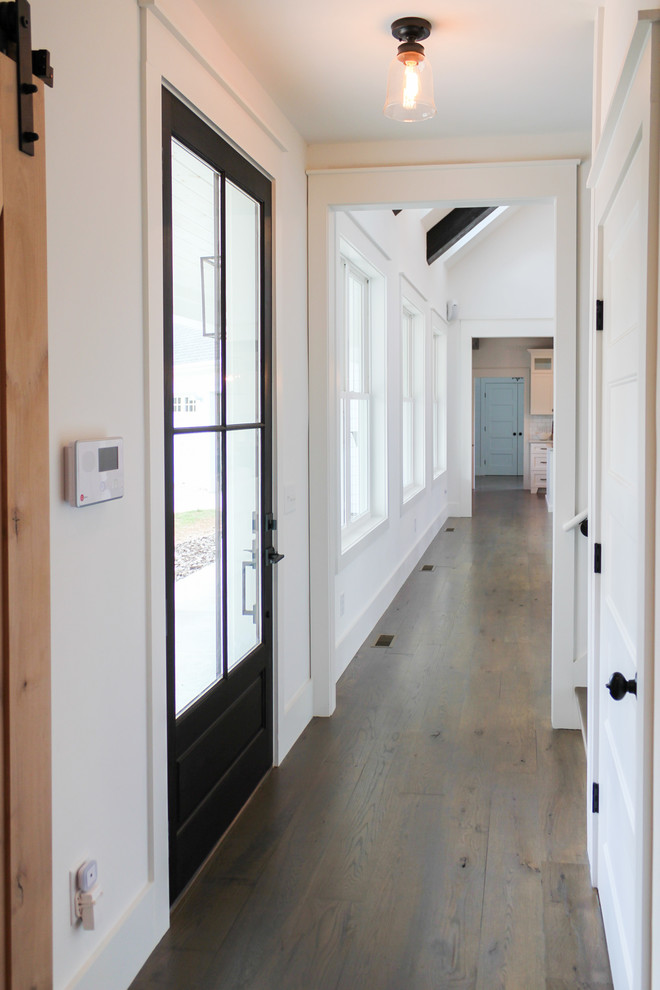 Idées déco pour une entrée campagne avec un couloir, un mur blanc, un sol en bois brun, une porte simple et une porte noire.