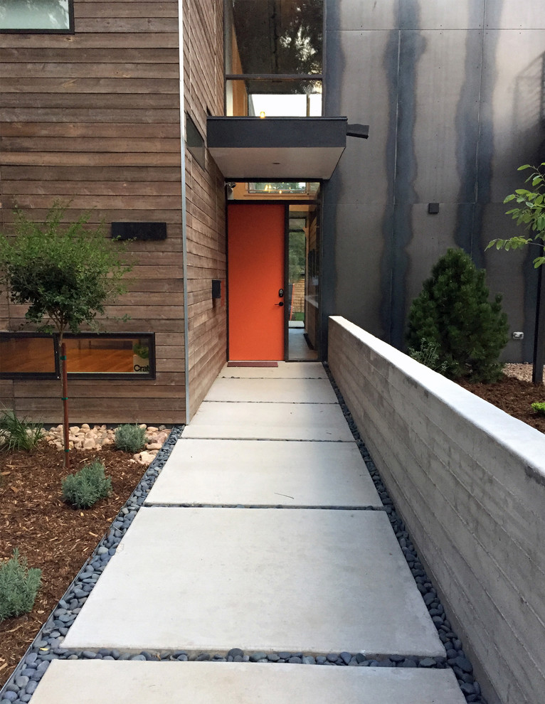デンバーにあるコンテンポラリースタイルのおしゃれな玄関ドア (茶色い壁、コンクリートの床、オレンジのドア) の写真
