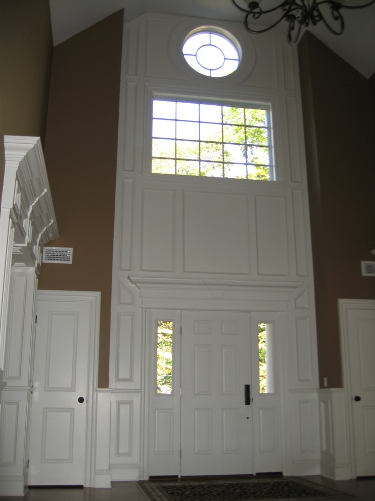 На фото: огромная входная дверь в классическом стиле с бежевыми стенами, темным паркетным полом, одностворчатой входной дверью и белой входной дверью