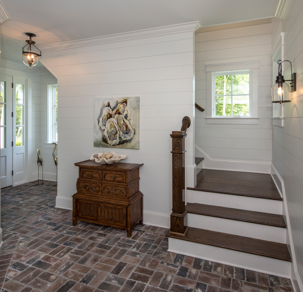 Esempio di un ingresso stile marinaro di medie dimensioni con pareti bianche, pavimento in mattoni, una porta singola e una porta bianca