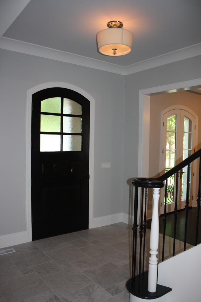 Cette image montre une grande porte d'entrée traditionnelle avec un mur gris, un sol en marbre, une porte simple et une porte en bois foncé.