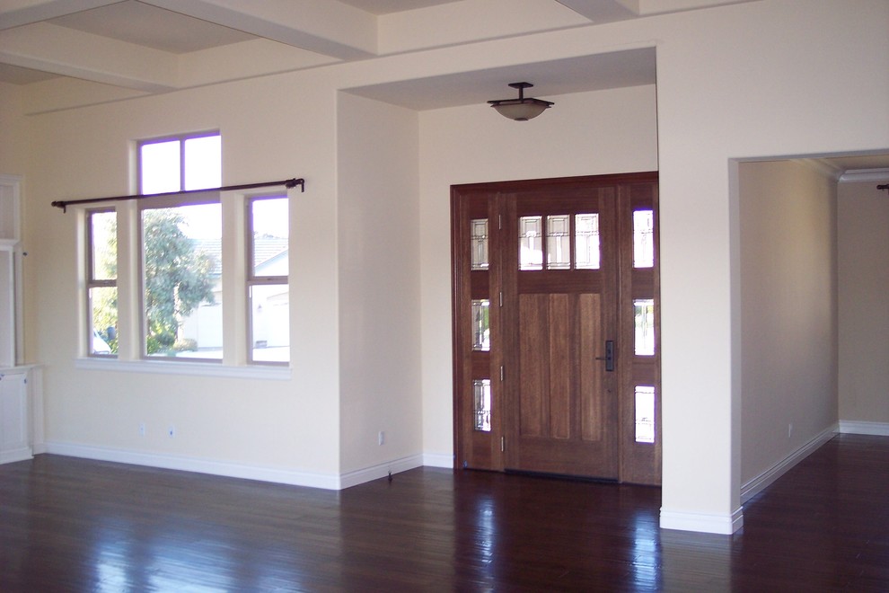 Imagen de puerta principal moderna de tamaño medio con paredes beige, suelo de madera oscura, puerta simple y puerta de madera en tonos medios