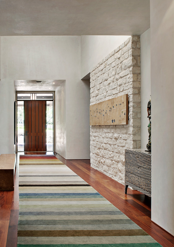 Foto de hall contemporáneo con paredes blancas, suelo de madera en tonos medios, puerta simple y puerta de madera en tonos medios
