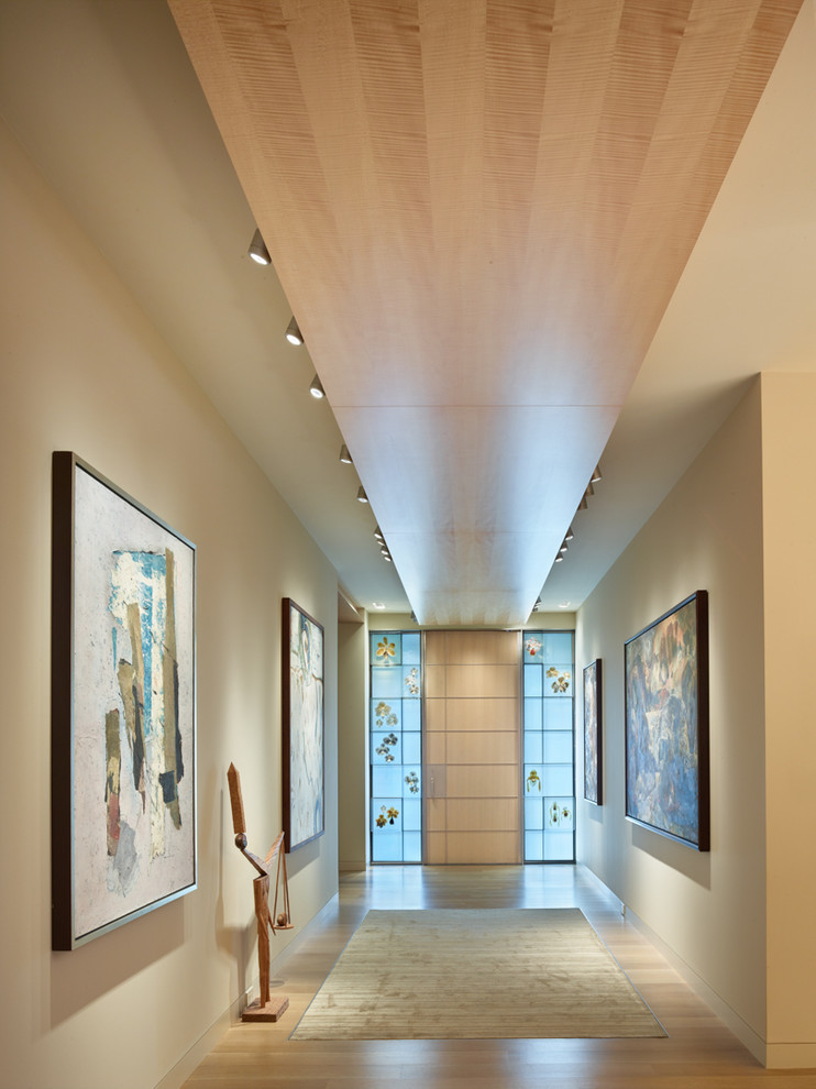 Idées déco pour une entrée contemporaine avec un couloir, un mur beige, une porte simple et parquet clair.