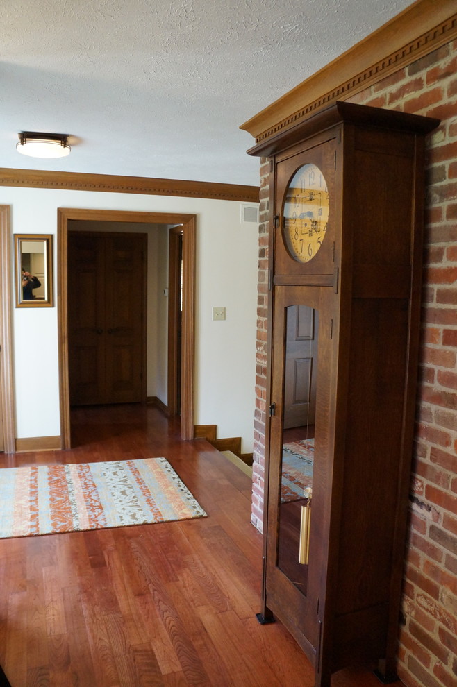 Cette image montre une entrée craftsman de taille moyenne avec un couloir, un mur beige, un sol en bois brun, une porte en verre et une porte simple.