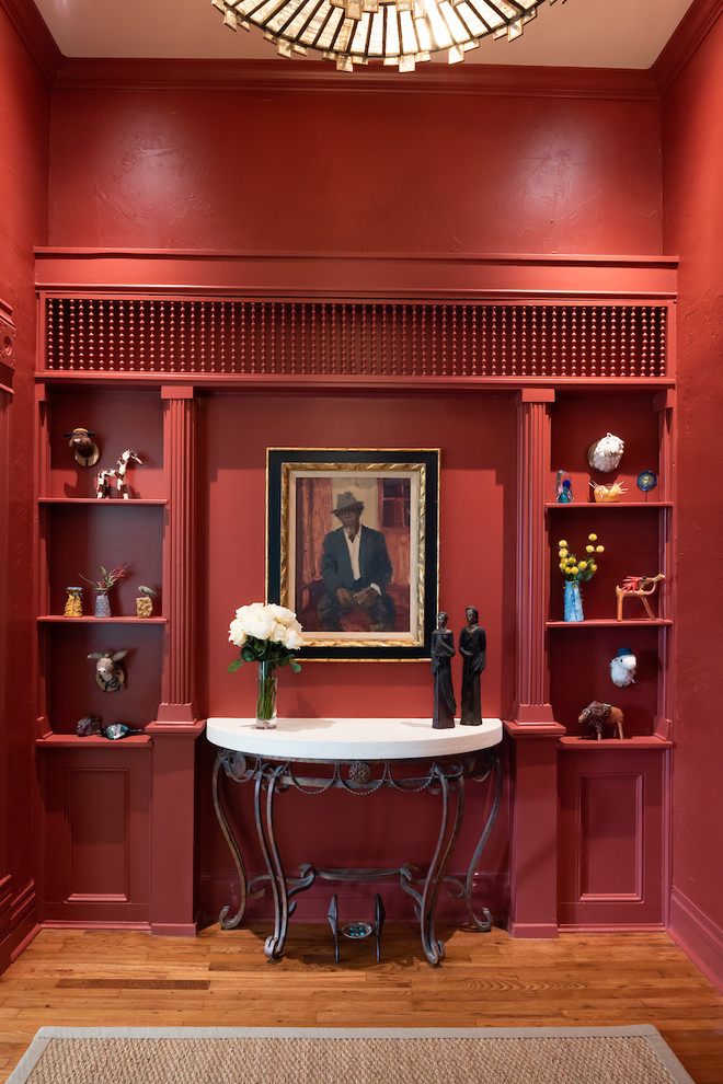 Imagen de entrada bohemia con paredes rojas y suelo de madera en tonos medios