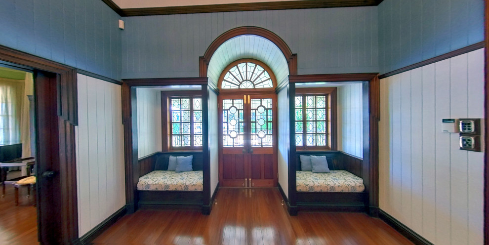 ブリスベンにある広いトラディショナルスタイルのおしゃれな玄関ロビー (青い壁、無垢フローリング、木目調のドア、三角天井、板張り壁) の写真