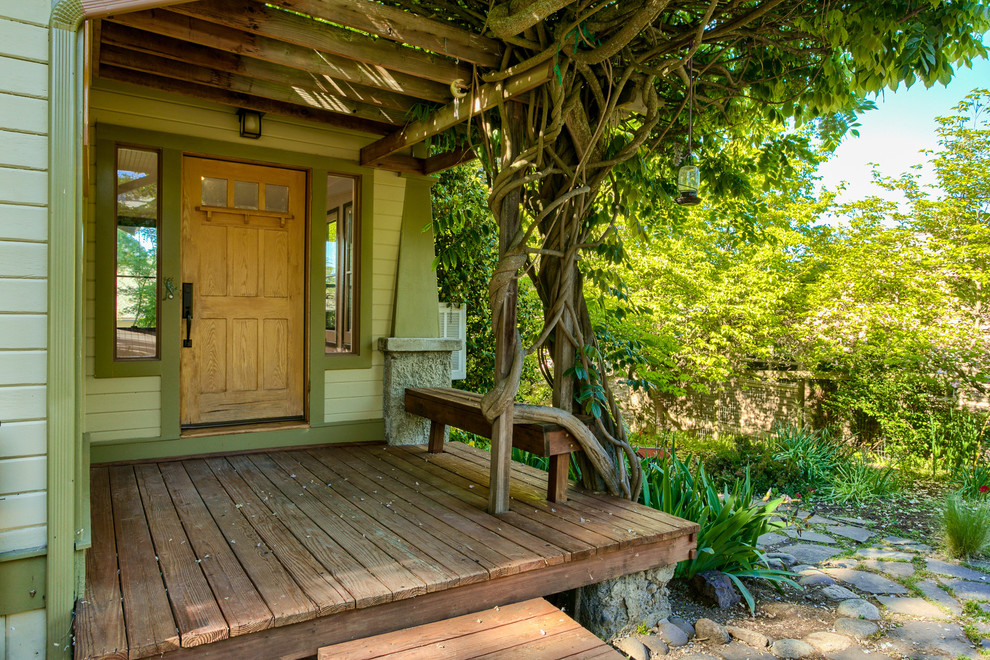 Cette photo montre une petite porte d'entrée craftsman avec un mur vert, parquet foncé, une porte simple, une porte en bois clair et un sol marron.