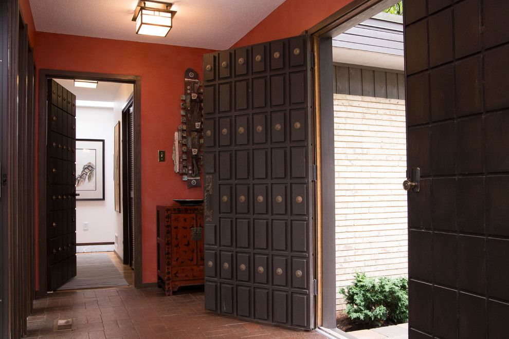 ローリーにあるお手頃価格の中くらいなミッドセンチュリースタイルのおしゃれな玄関ロビー (レンガの床、濃色木目調のドア、赤い壁、赤い床) の写真