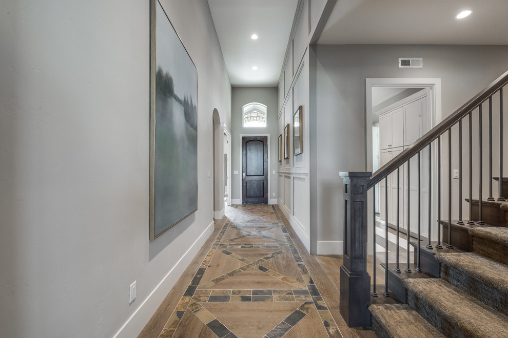 Esempio di un corridoio classico di medie dimensioni con pareti grigie, parquet chiaro, una porta singola, una porta in legno scuro e pavimento marrone