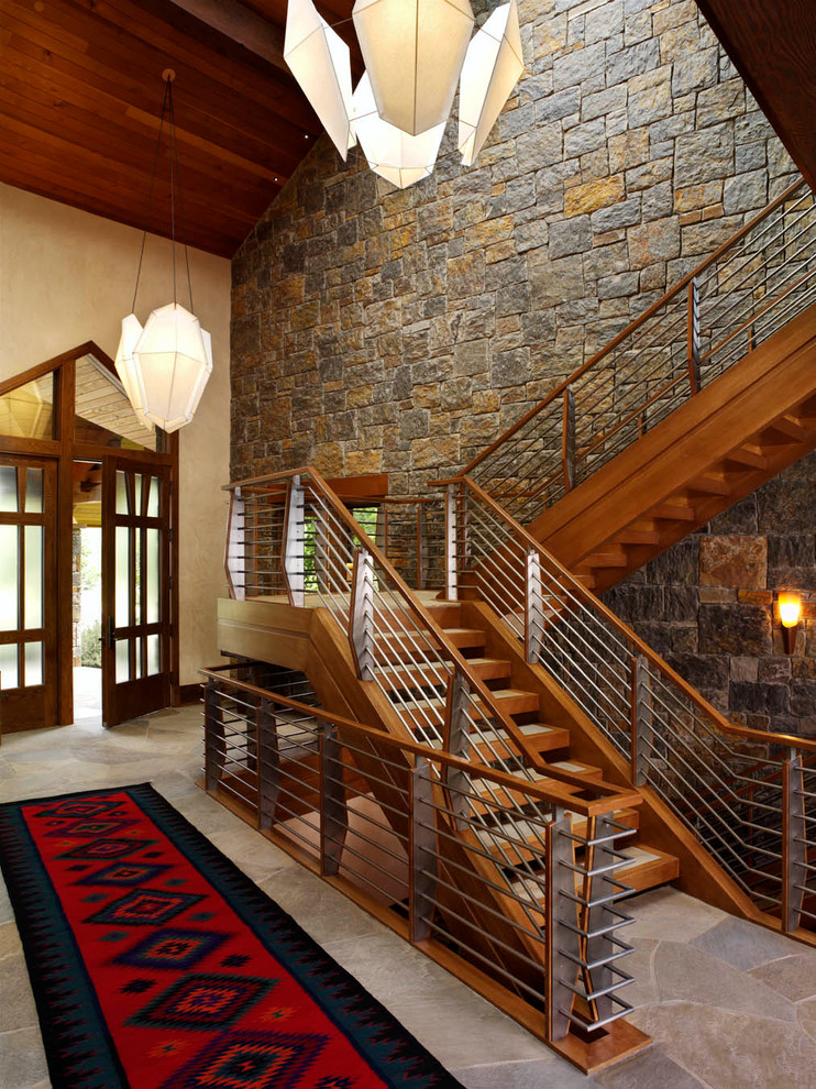 Exemple d'un grand hall d'entrée montagne avec un mur beige, un sol en ardoise, une porte double, une porte en verre et un sol multicolore.