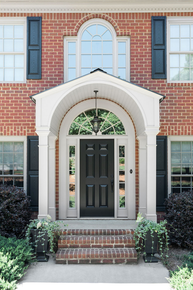 Exempel på en stor klassisk ingång och ytterdörr, med en enkeldörr och en svart dörr