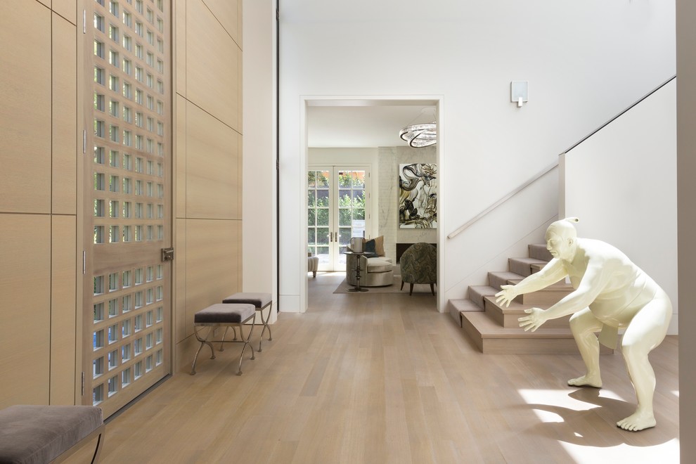 Réalisation d'une grande entrée design avec un couloir, un mur blanc, parquet clair, une porte simple et une porte en bois clair.