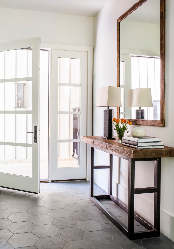 Inspiration for a farmhouse foyer in Atlanta with white walls, a single front door, a glass front door, grey floors and feature lighting.