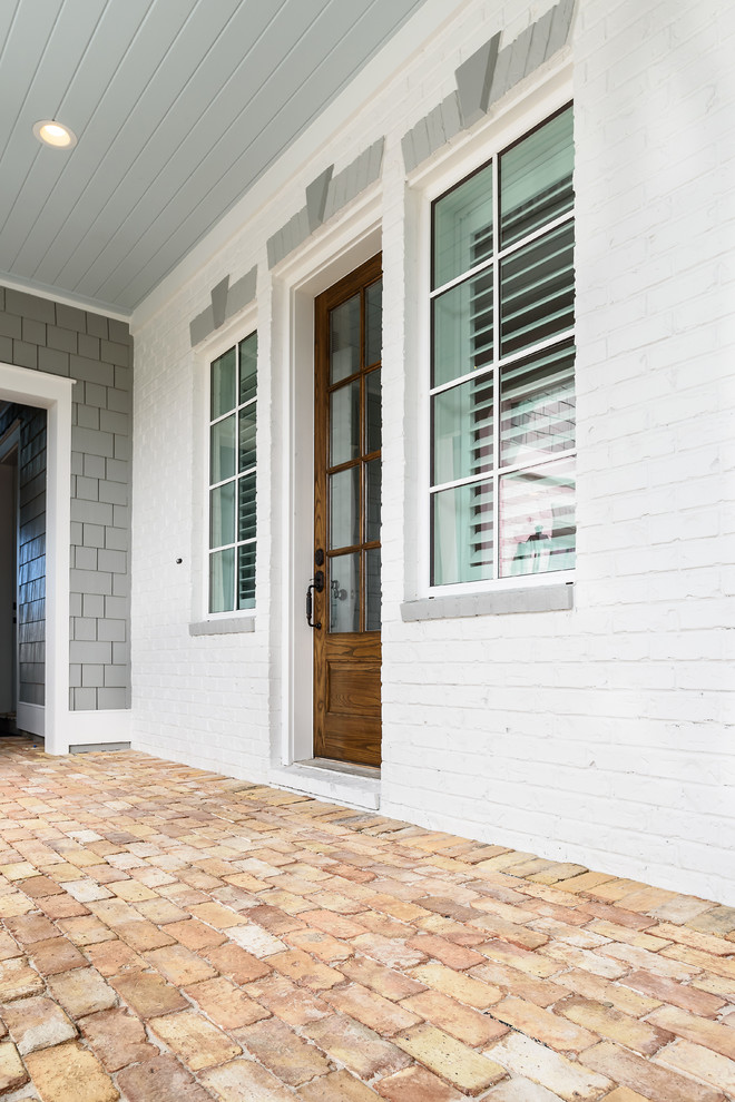 Foto di una porta d'ingresso stile marino di medie dimensioni con pareti bianche, pavimento in mattoni, una porta singola, una porta in legno scuro e pavimento marrone