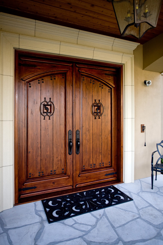 シアトルにあるラグジュアリーな広い地中海スタイルのおしゃれな玄関ドア (ベージュの壁、スレートの床、濃色木目調のドア) の写真
