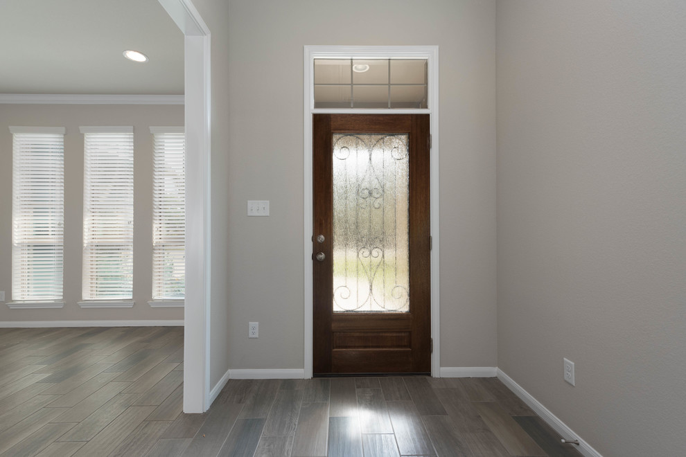 オースティンにある高級な中くらいなトラディショナルスタイルのおしゃれな玄関ドア (ベージュの壁、ラミネートの床、木目調のドア、マルチカラーの床) の写真