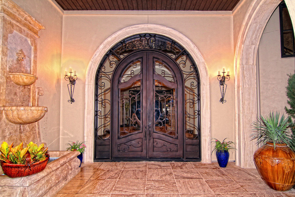 На фото: огромная входная дверь в средиземноморском стиле с полом из травертина, двустворчатой входной дверью, коричневой входной дверью и разноцветным полом с