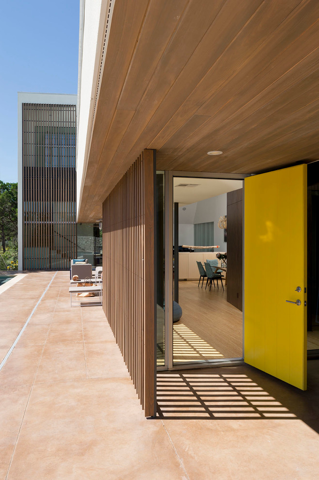Cette image montre une porte d'entrée minimaliste avec une porte simple et une porte jaune.