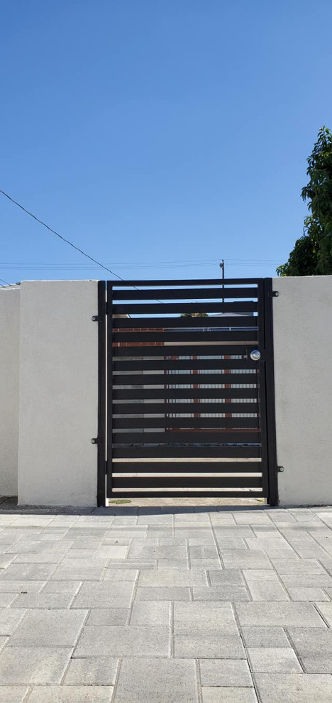 Immagine di un ingresso o corridoio minimalista con una porta singola, una porta in metallo e pavimento grigio