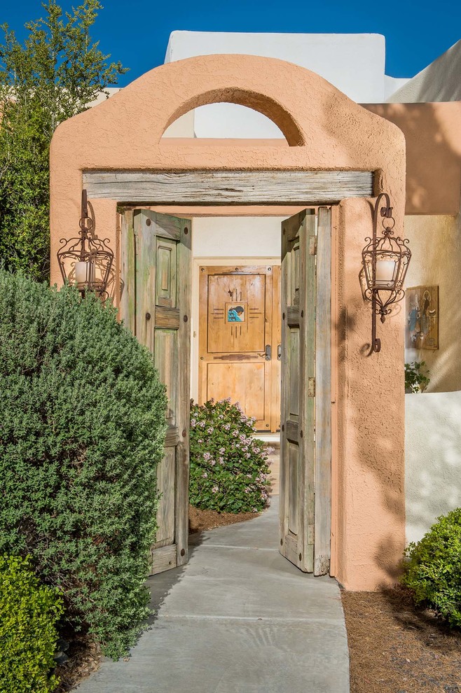 Пример оригинального дизайна: входная дверь в средиземноморском стиле с оранжевыми стенами, двустворчатой входной дверью и входной дверью из дерева среднего тона