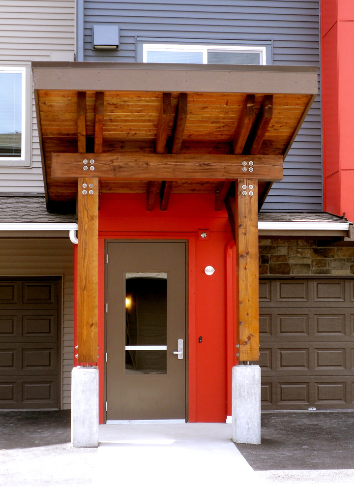 Ispirazione per una porta d'ingresso moderna con pareti rosse, pavimento in cemento, una porta singola e una porta marrone