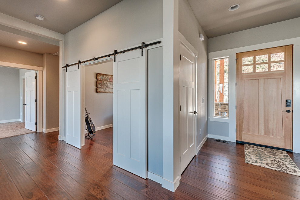Esempio di un ingresso o corridoio stile americano di medie dimensioni con pareti grigie, pavimento in legno massello medio, una porta singola e una porta in legno chiaro