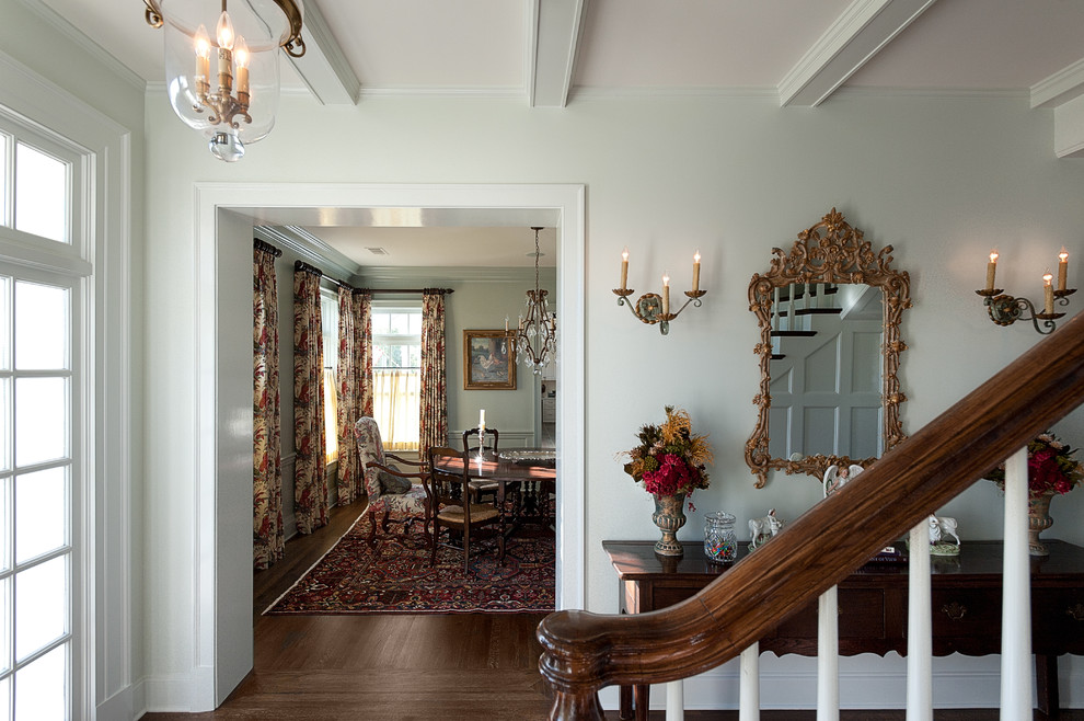 На фото: фойе среднего размера в классическом стиле с белыми стенами, темным паркетным полом и одностворчатой входной дверью с