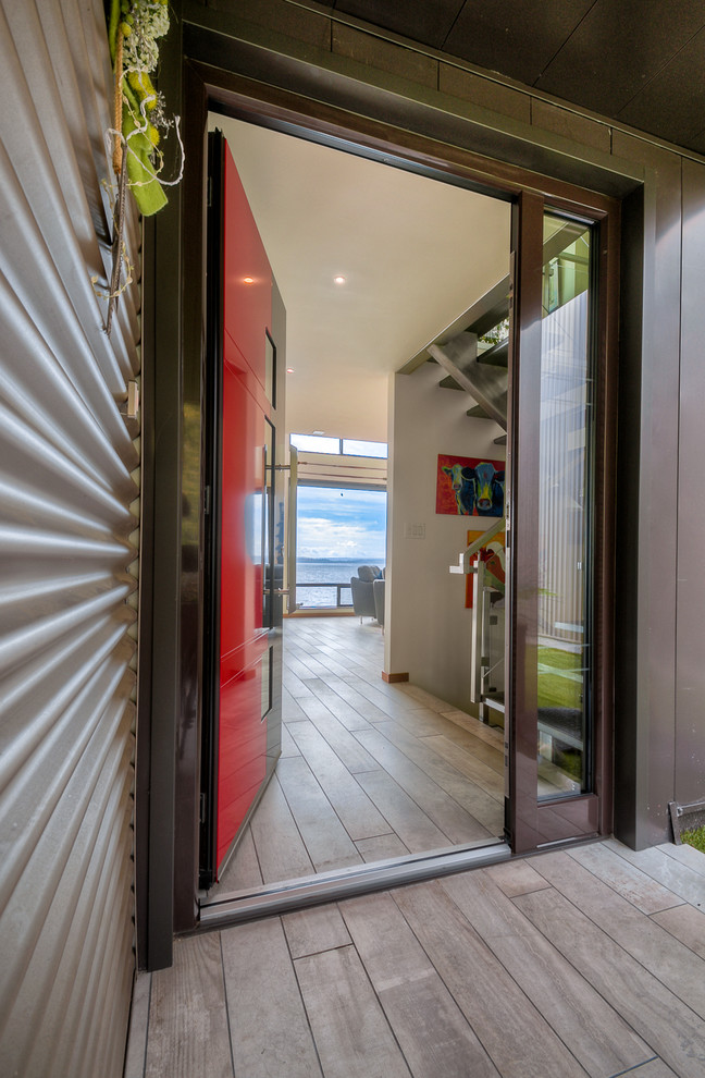 Aménagement d'une grande porte d'entrée moderne avec un mur blanc, parquet clair, une porte simple, une porte rouge et un sol gris.