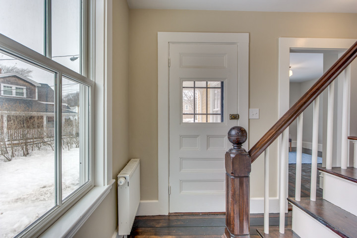 Modelo de puerta principal clásica de tamaño medio con paredes beige, suelo de madera oscura, puerta simple y puerta azul