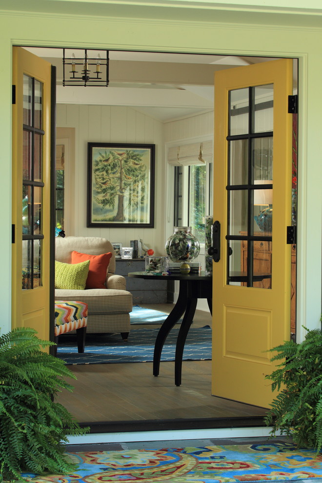 Modelo de puerta principal marinera de tamaño medio con paredes blancas, suelo de madera en tonos medios, puerta doble y puerta amarilla