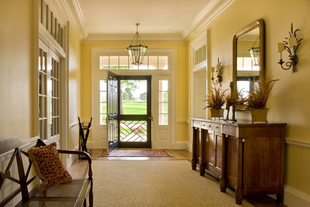 Großer Klassischer Eingang mit Korridor, gelber Wandfarbe, braunem Holzboden, Einzeltür und schwarzer Haustür in Washington, D.C.