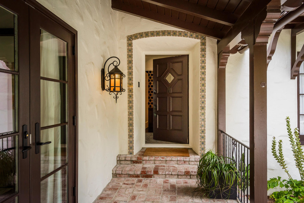 Cette image montre une porte d'entrée traditionnelle avec un sol en brique, une porte simple et une porte marron.