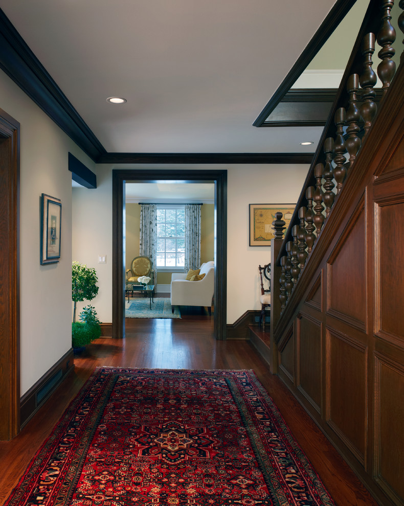 Réalisation d'un grand hall d'entrée craftsman avec un mur blanc, un sol en bois brun, une porte simple et une porte en bois brun.