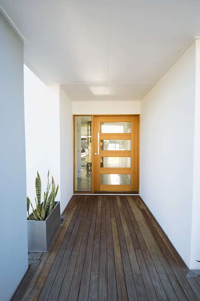 Ispirazione per un ingresso o corridoio nordico con pareti bianche, pavimento in legno verniciato, una porta a pivot e una porta in legno chiaro