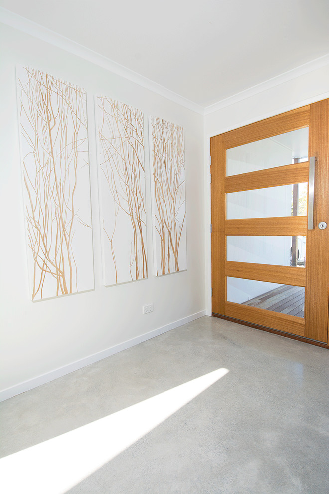 Источник вдохновения для домашнего уюта: прихожая в скандинавском стиле с белыми стенами, бетонным полом, поворотной входной дверью и входной дверью из светлого дерева